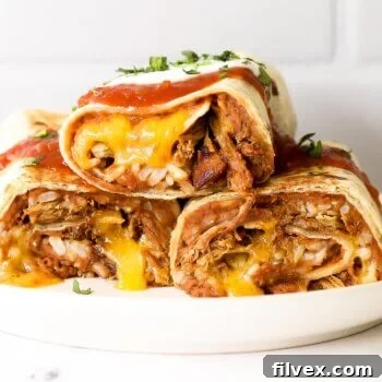 Straight on shot of 3 baked carnitas burritos on a plate with salsa and sour cream on top