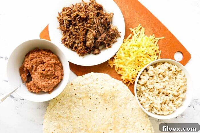 Overhead shot of burrito tortilla, refried beans, carnitas, cheese and rice