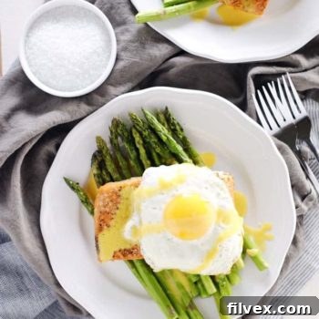 Close-up of roasted salmon and asparagus with a generous drizzle of hollandaise sauce.
