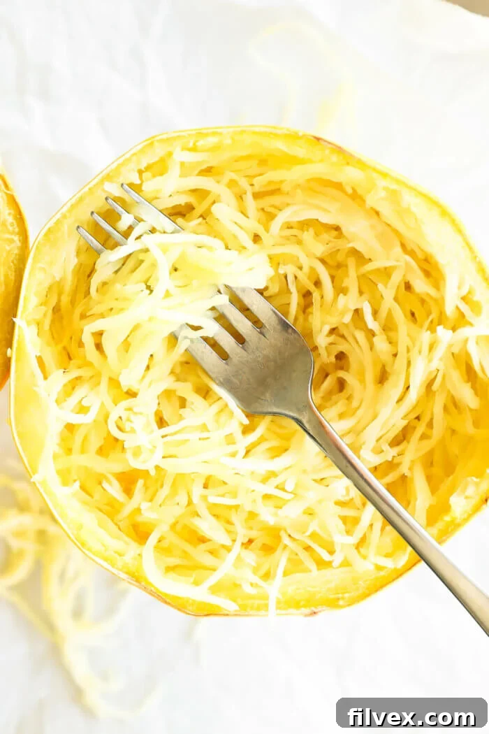 Spaghetti squash noodles all scooped out in the shell with a fork with noodles wrapped around it.