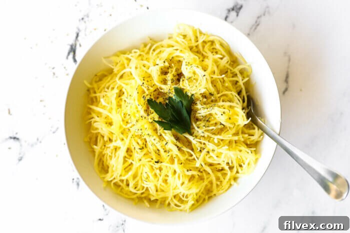 Overhead image of a bowl full of spaghetti squash noodles with herbs sprinkled on top. A fork is in the bowl with noodles wrapped around it.