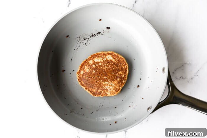 Pancake flipped in skillet once bubbles appear and edges look slightly rounded.