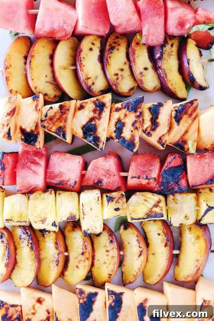 Close-up of grilled fruit skewers featuring watermelon, peaches, cantaloupe, and pineapple.