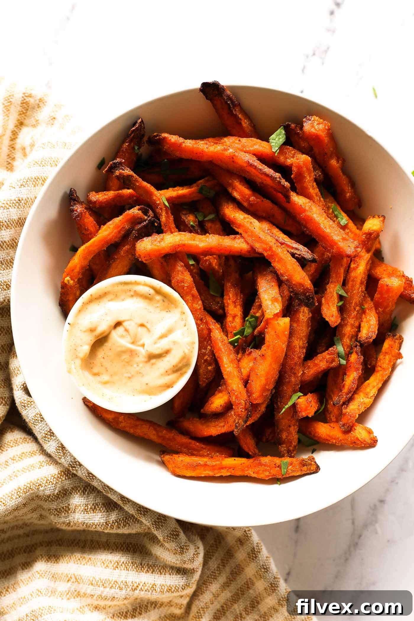 Perfectly crispy air fryer sweet potato fries in a bowl, ready to serve with a side of dipping sauce