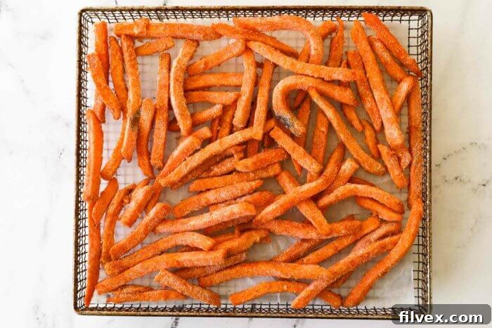 Frozen, seasoned sweet potato fries evenly spread in an air fryer basket