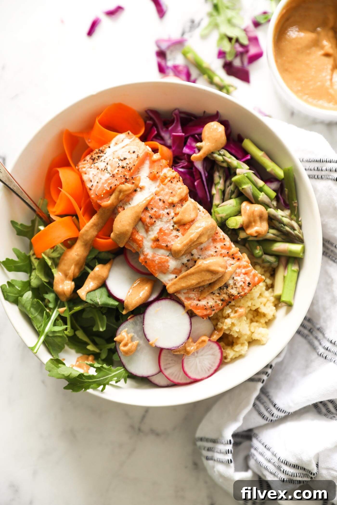 Overhead shot of a colorful salmon buddha bowl with various vegetables and salmon