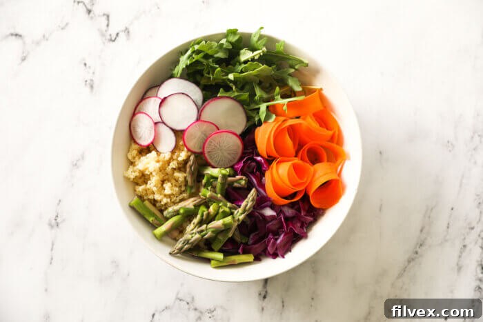 Carrots, cabbage, asparagus, millet, radish and arugula separated out in a bowl.