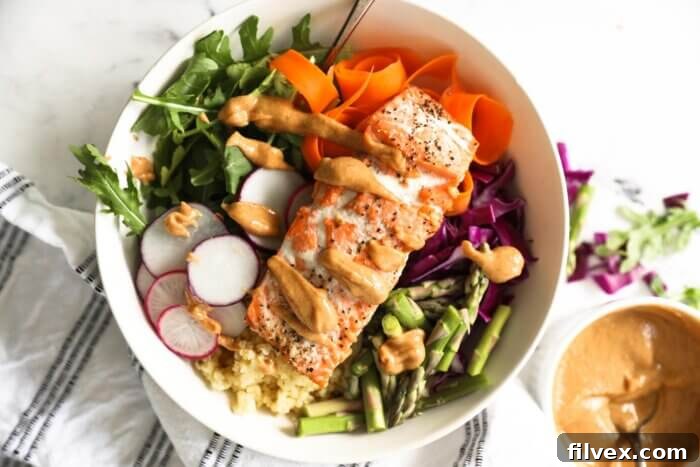 Cooked salmon buddha bowl with peanut sauce drizzled over the top