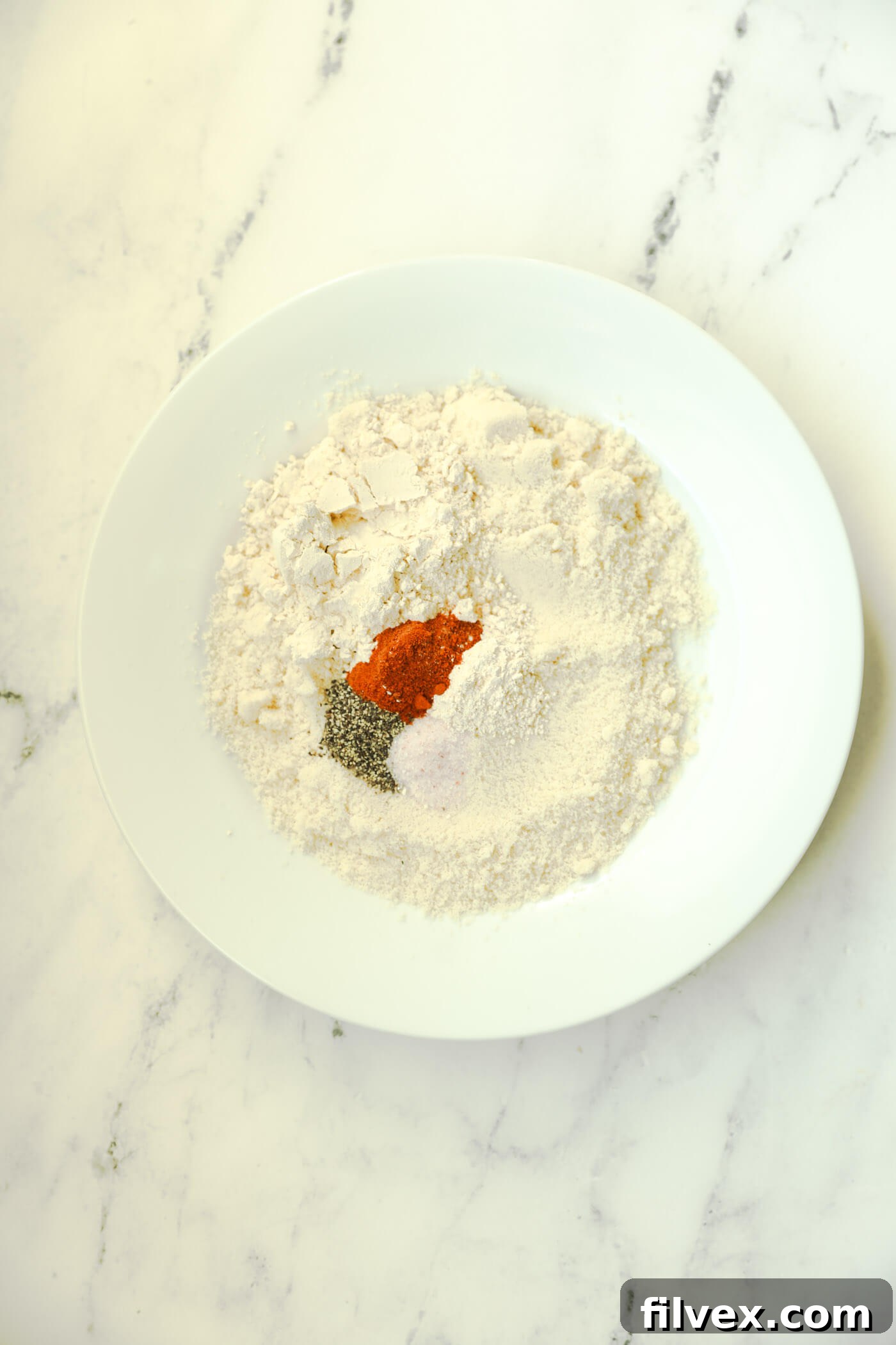 Almond flour, chickpea flour, and seasonings spread on a plate for the breading mixture.