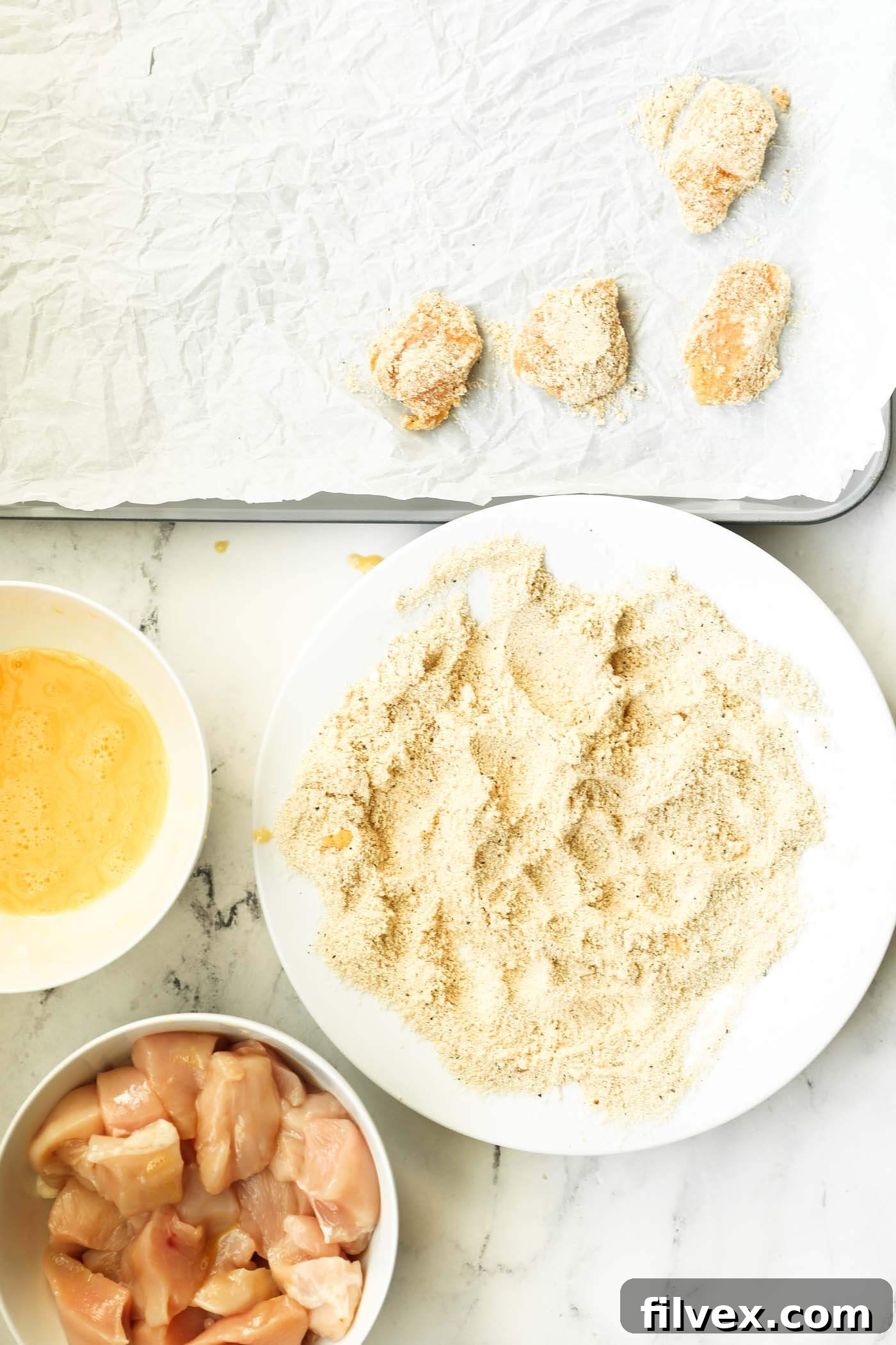 A breaded keto chicken nugget placed on a baking sheet.