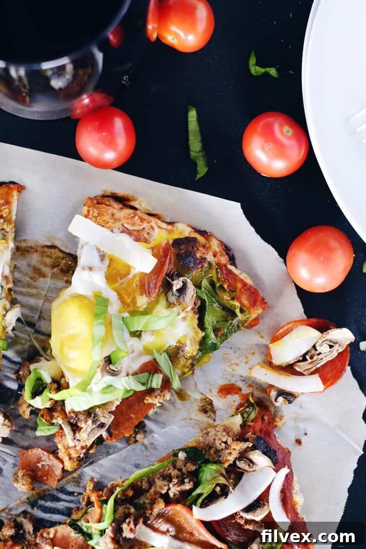 A vibrant close-up of our Paleo Breakfast Pizza, packed with savory sausage, crisp pepperoni, tender mushrooms, fresh onion, wholesome spinach, and perfectly cooked, gooey eggs. A gluten-free and dairy-free breakfast for dinner delight from realsimplegood.com