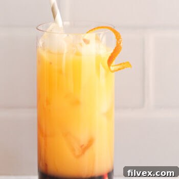 Orange sunrise mocktail in a jar with a straw coming out and orange peel garnish, photographed from above.