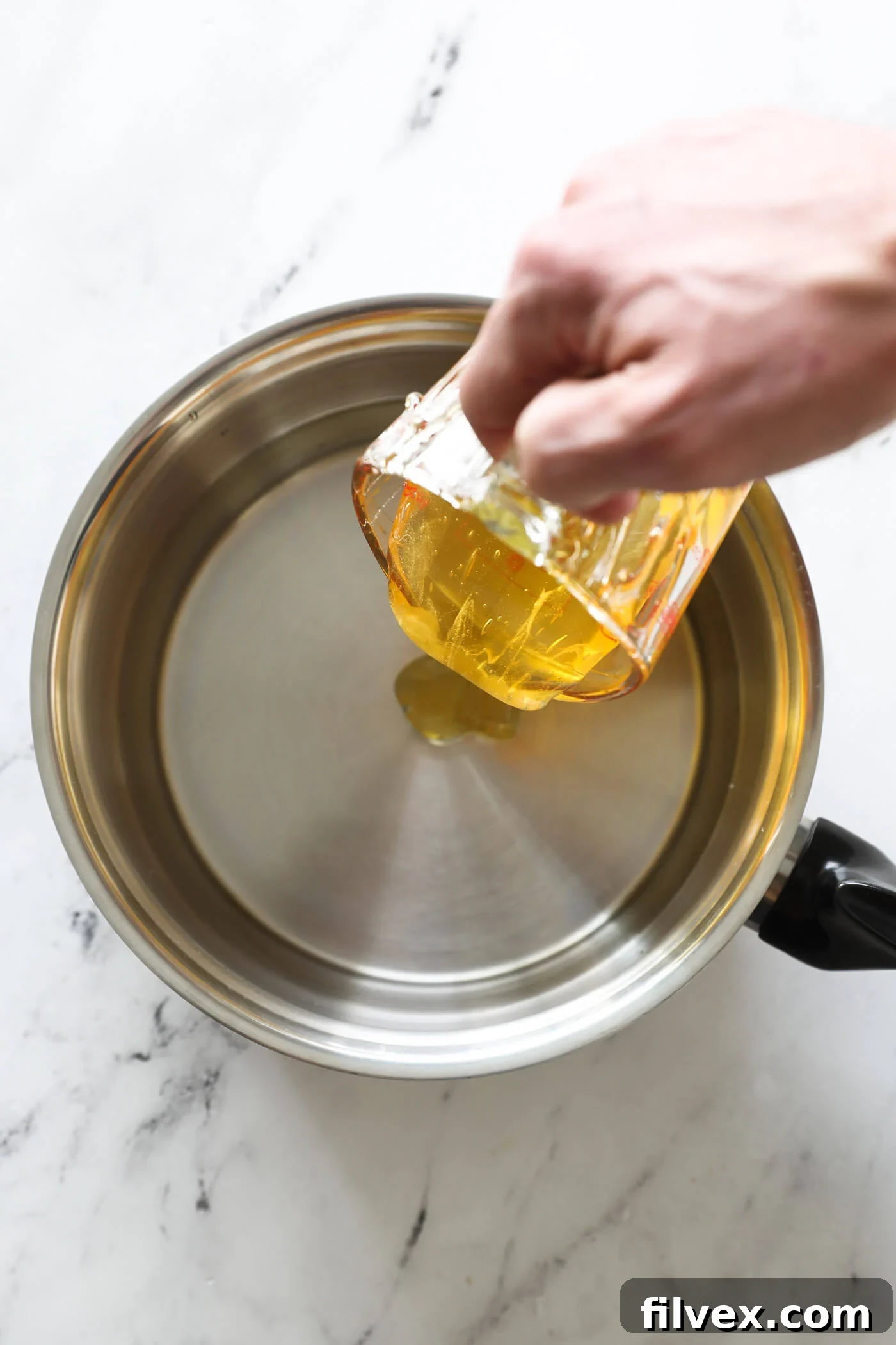 Adding water and honey to a small pan over medium-high heat.