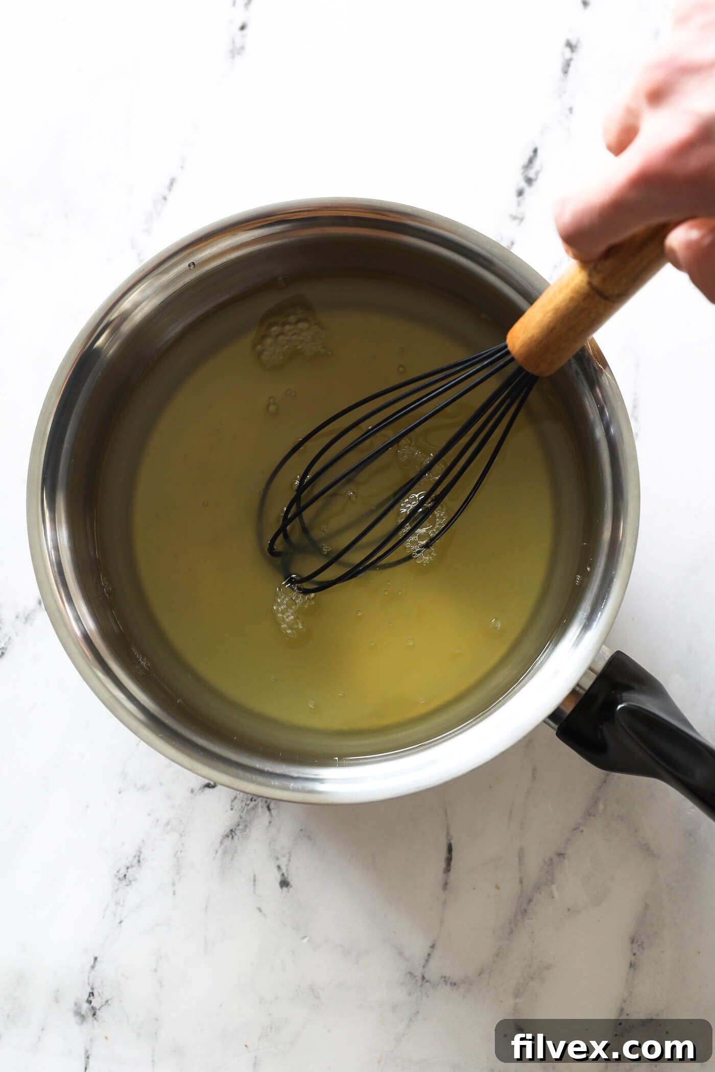 Stirring the honey and water mixture as it comes to a low simmer.