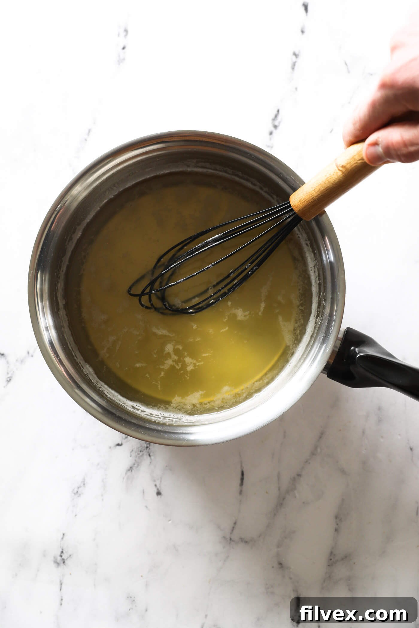 Honey syrup simmering and thickening, with frequent stirring.