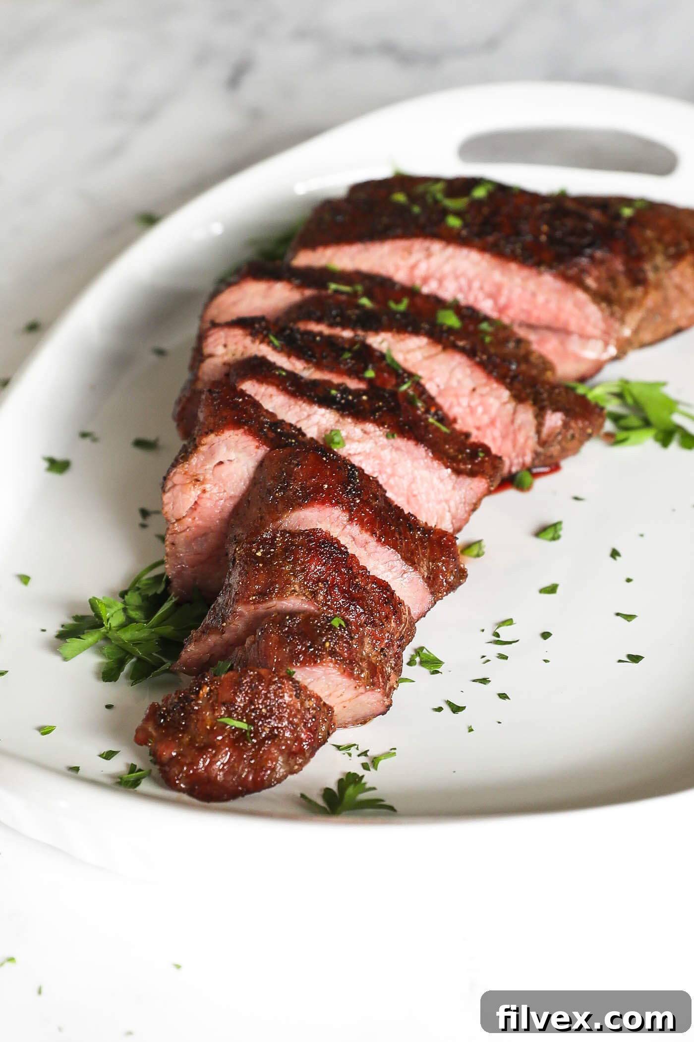 Sliced smoked tri-tip on a platter, showing medium-rare doneness.
