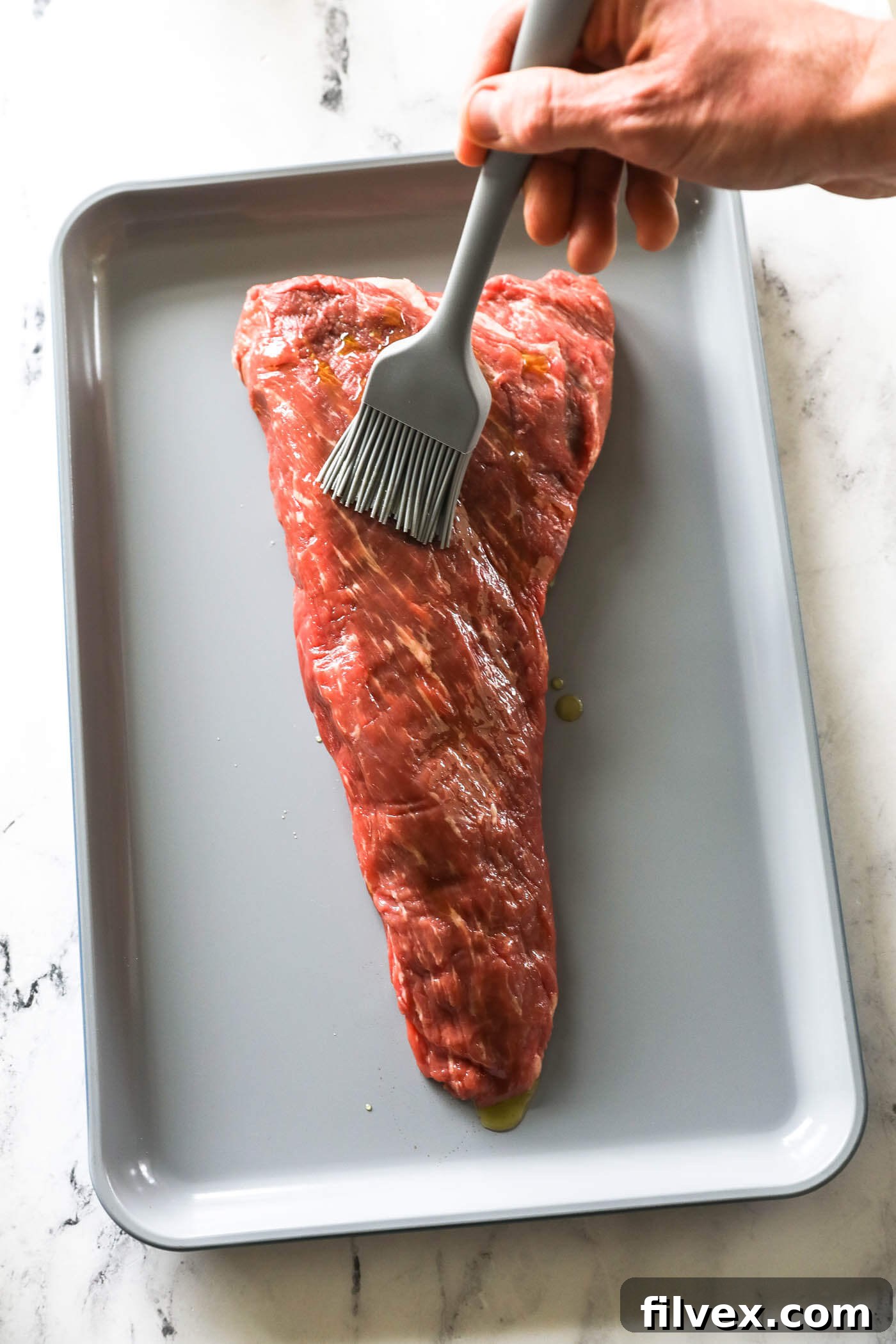 Olive oil drizzled over the tri-tip roast, ready to be brushed.