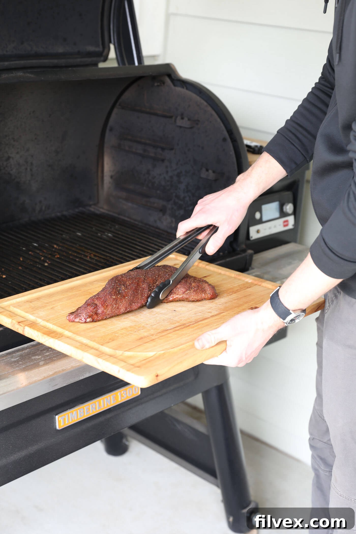 Smoked tri-tip roast being removed from the smoker and placed on a cutting board.