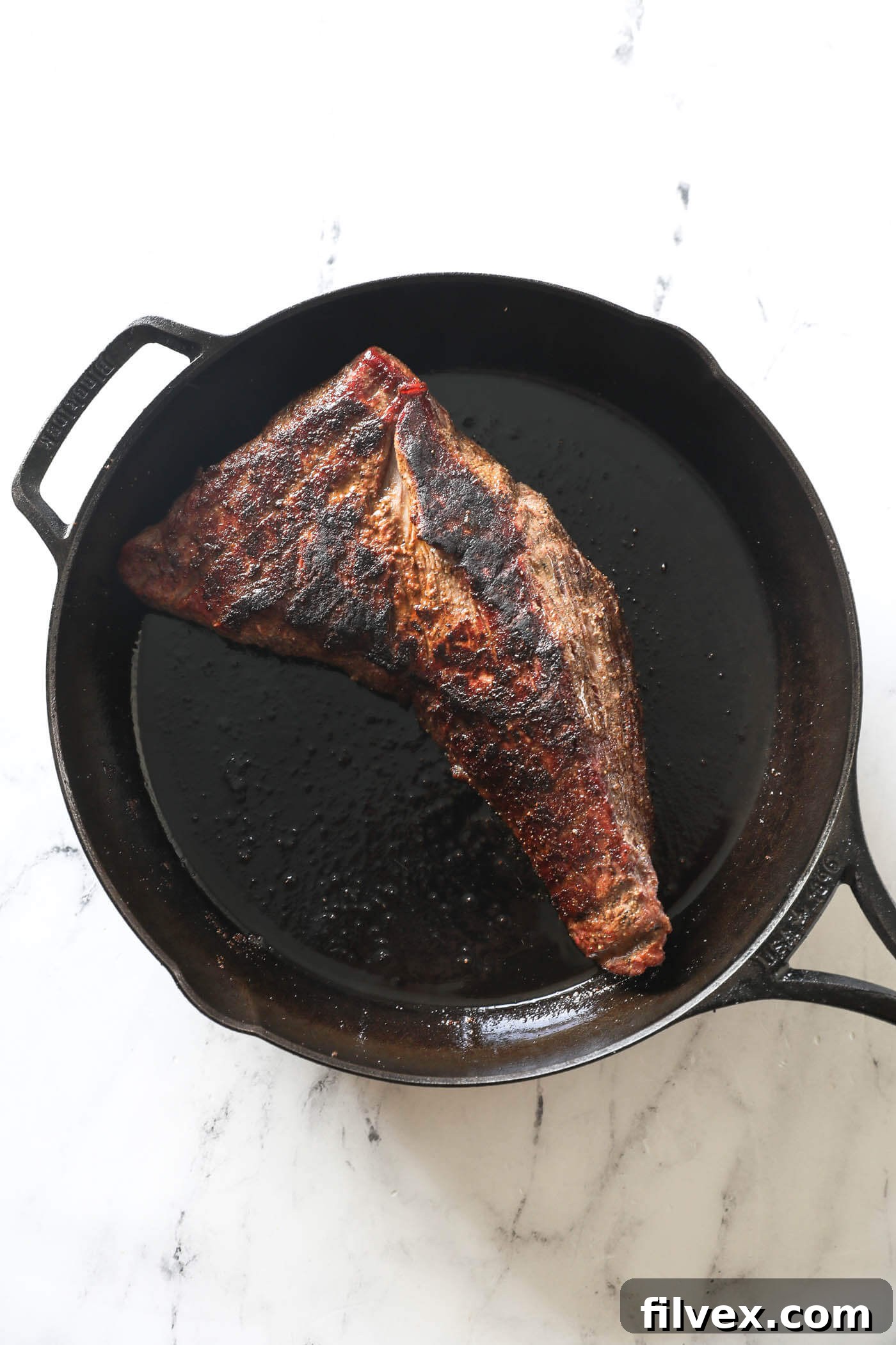 Tri-tip searing in a hot cast iron pan, creating a crispy crust.