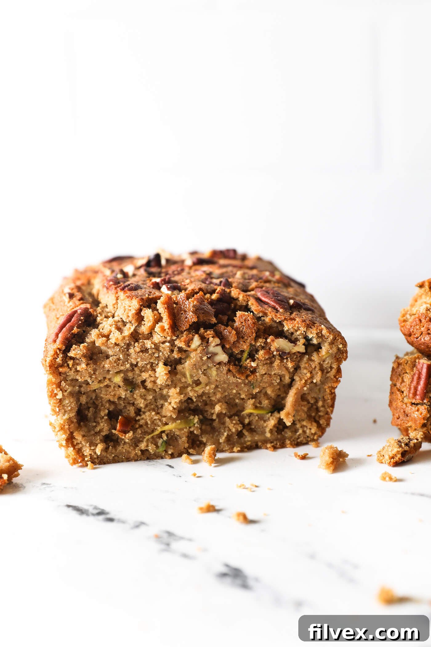 Straight on shot of a loaf of zucchini bread with a couple of pieces sliced off to see the texture of the bread.