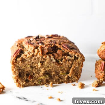 Straight on shot of a loaf of zucchini bread with a couple of pieces sliced off to see the texture of the bread.