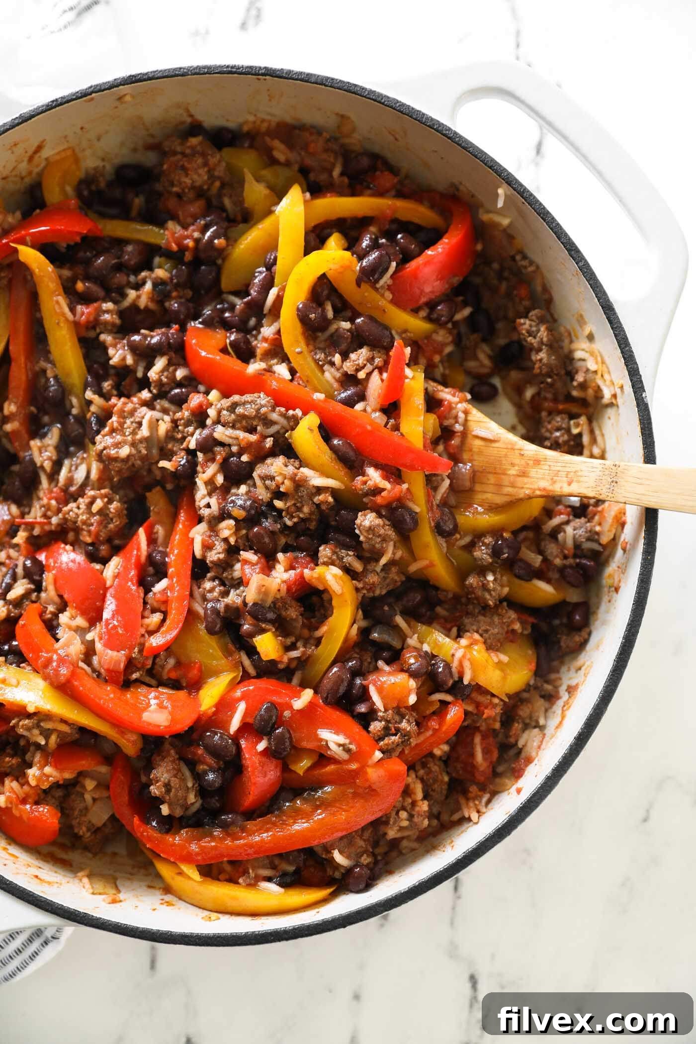 A top-down view of deconstructed stuffed peppers in a large skillet, showing ground beef, colorful bell peppers, tender rice, and diced tomatoes mingling together, perfectly cooked and ready to serve.