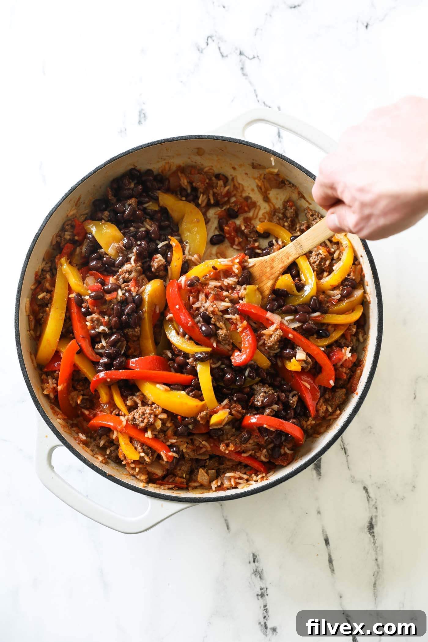 A generous serving of deconstructed stuffed peppers scooped into a bowl, topped with fresh green herbs, displaying the rich textures and inviting colors of this hearty meal.