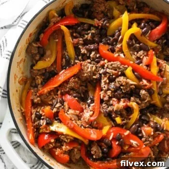 Close up overhead shot of deconstructed stuffed peppers in a pan with rice, beef and beans.