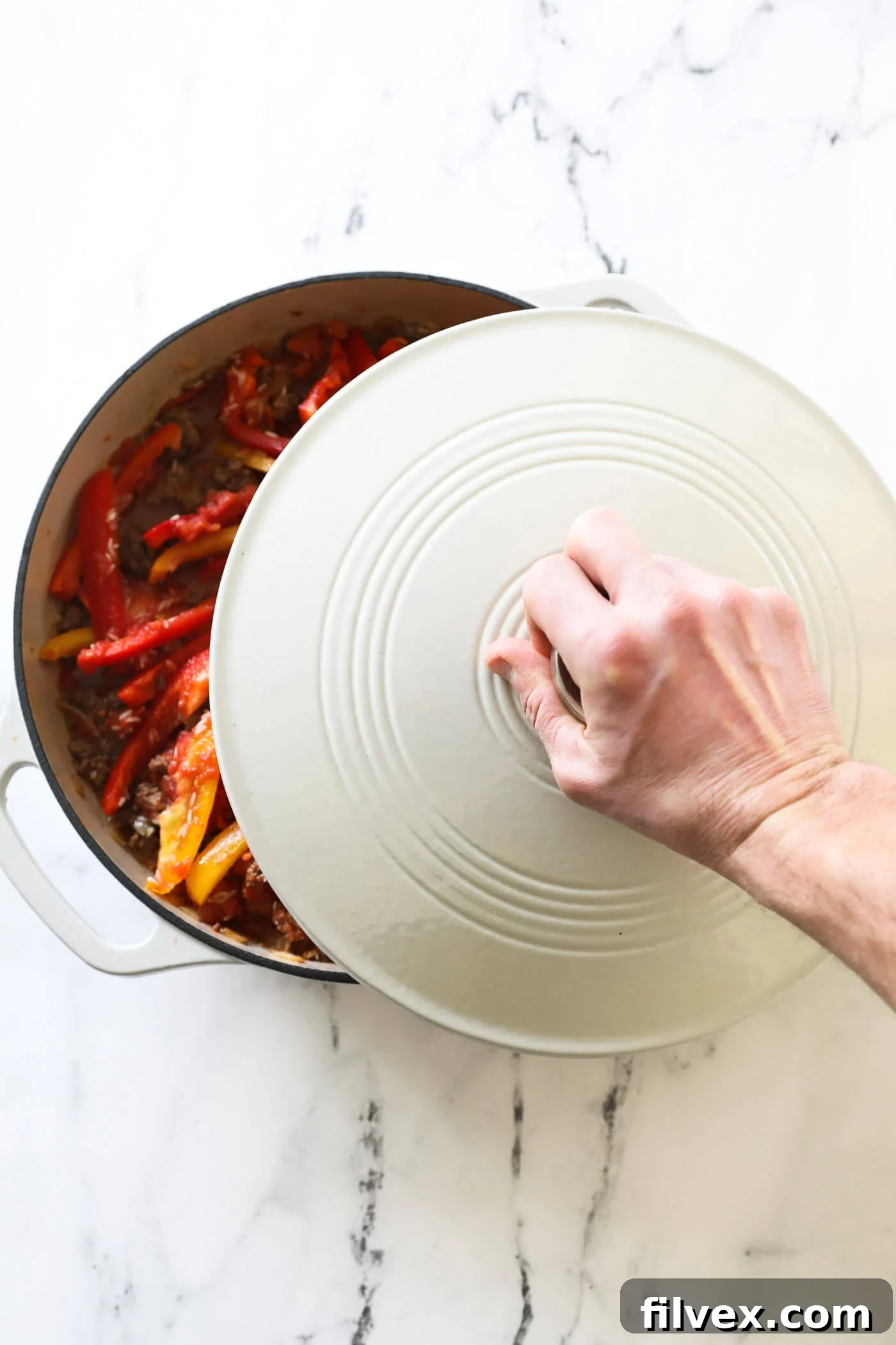 A large skillet with a lid, gently simmering on a stovetop burner, signifying the crucial cooking phase where the rice absorbs liquid and softens.