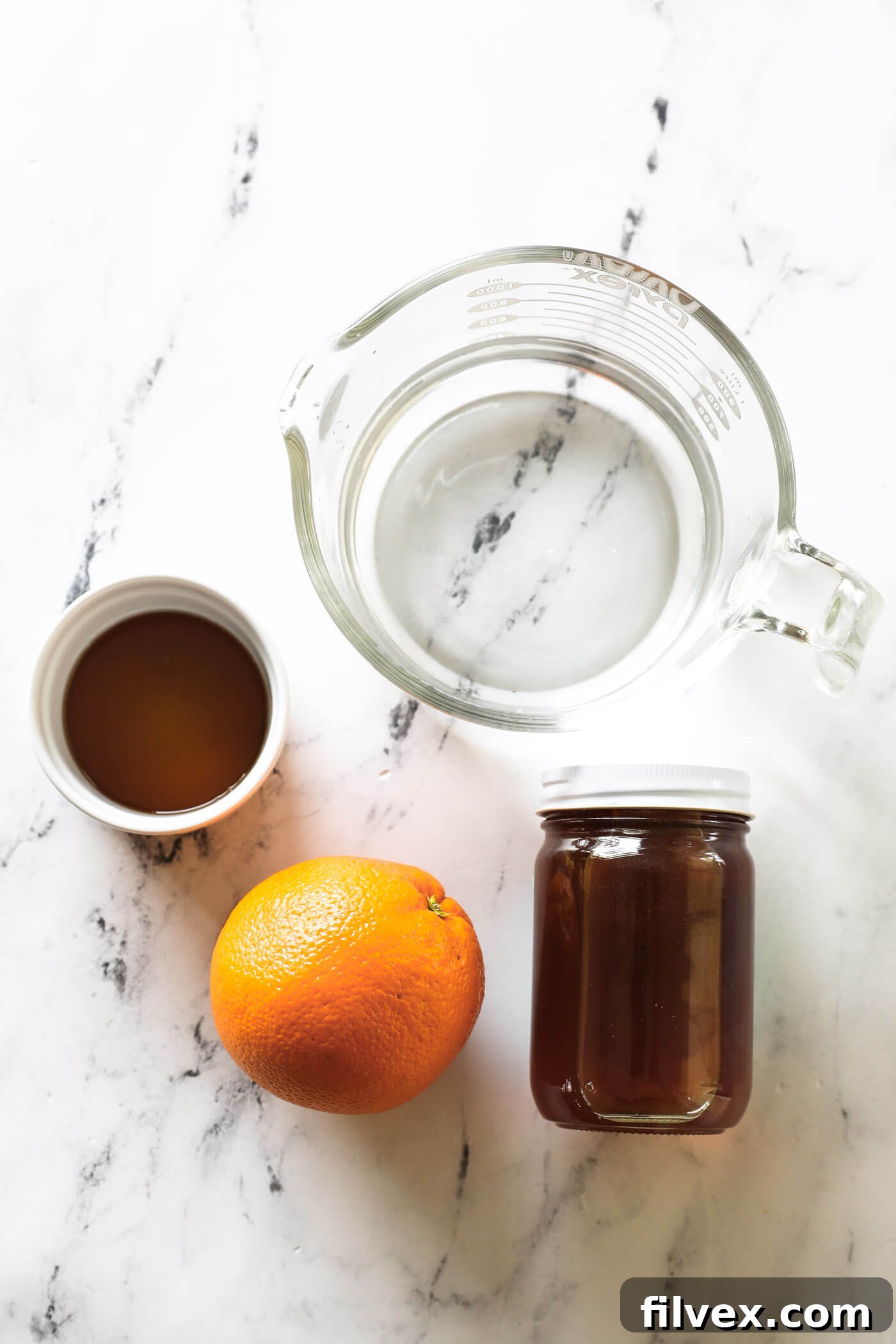Four essential ingredients for non-alcoholic triple sec: water, honey, maple syrup, and one fresh orange