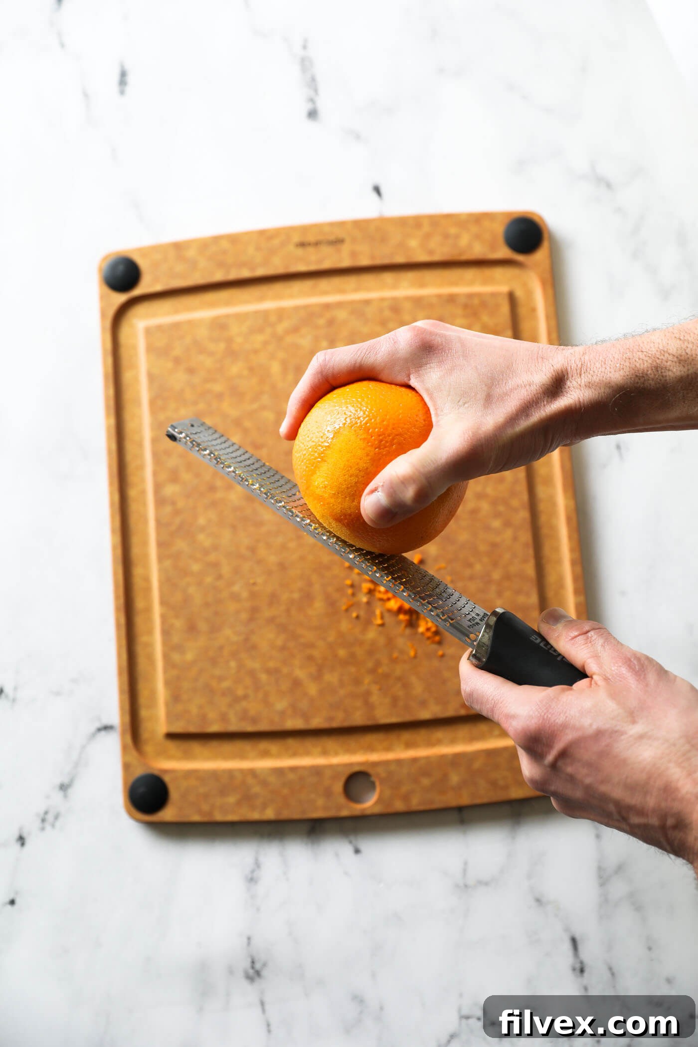 Orange zest being grated directly into the saucepan containing the syrup mixture