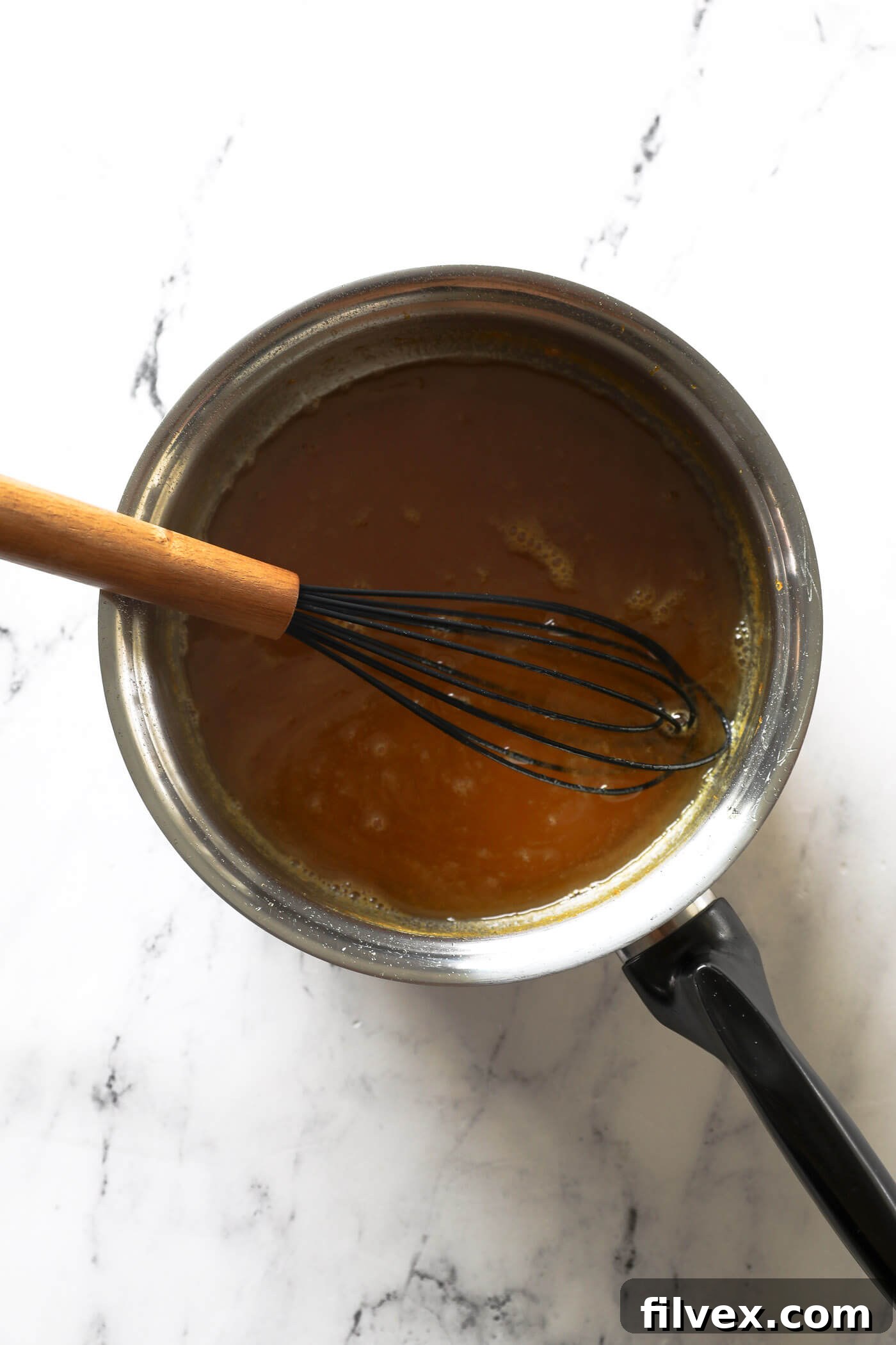 Orange syrup simmering in a saucepan, reducing and thickening