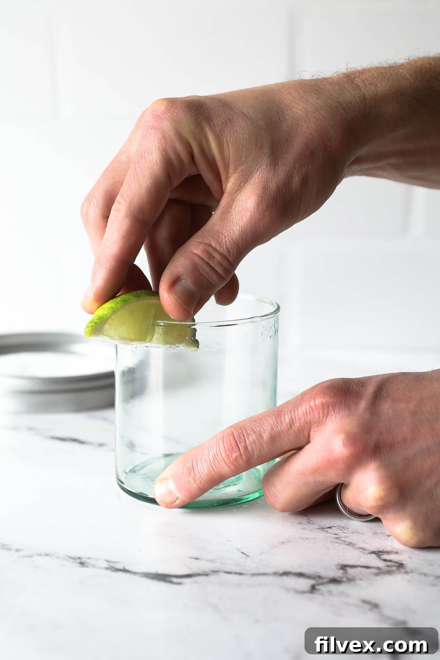 Lime wedge being rubbed around a glass rim for a salted edge.