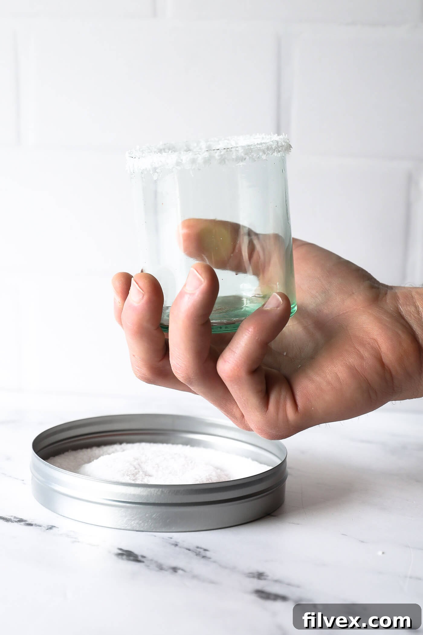 Glass rim being dipped into coarse salt for a perfect margarita finish.