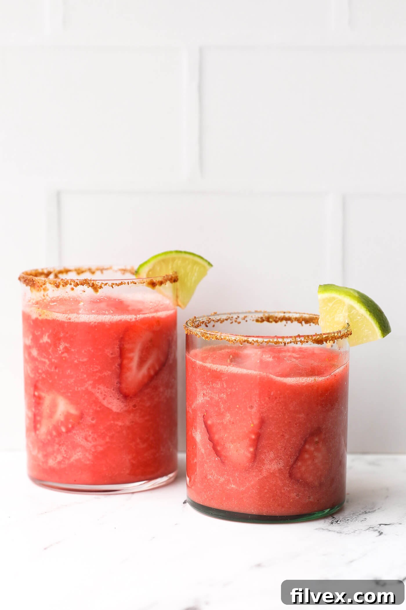 Vibrant red frozen strawberry daiquiri mocktail in a glass, garnished with a fresh strawberry slice.