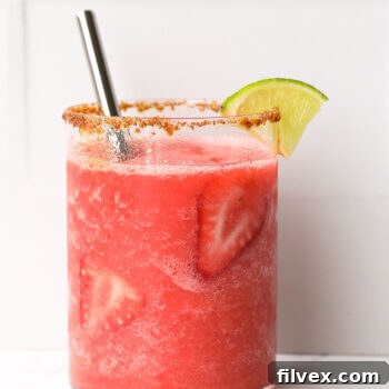 Close-up, straight-on shot of a single glass of frozen strawberry daiquiri mocktail, garnished beautifully.
