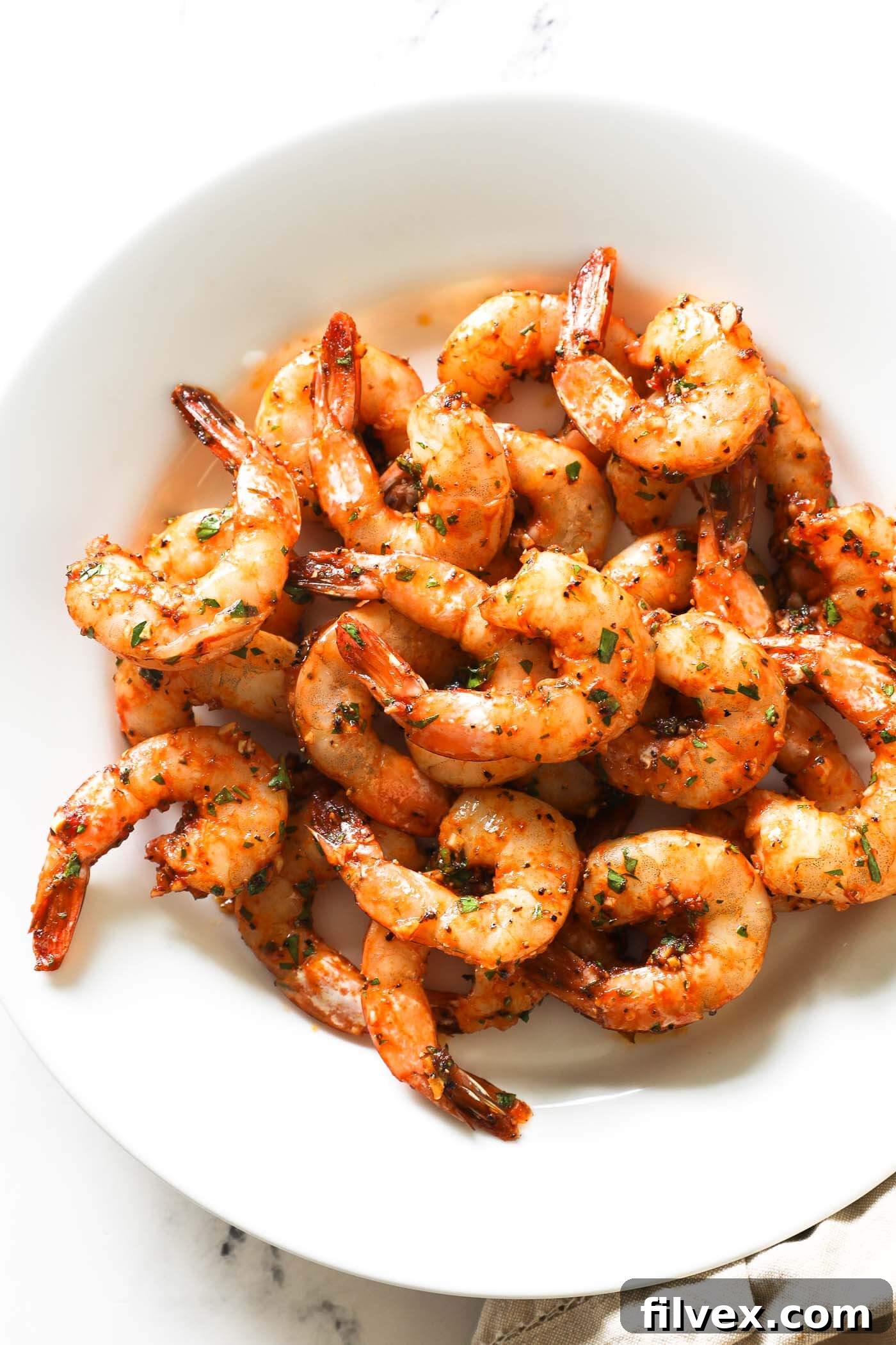 A beautifully arranged platter of golden, perfectly cooked garlic smoked shrimp, garnished with fresh herbs and lemon wedges, showcasing its appetizing appeal for a quick and flavorful meal or appetizer.