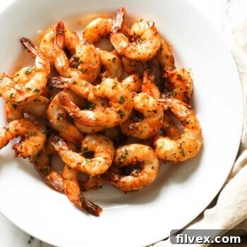 Overhead shot of a meticulously arranged plate of perfectly smoked garlic shrimp, garnished with fresh lemon wedges and a sprinkle of aromatic herbs, highlighting its exquisite readiness to serve.