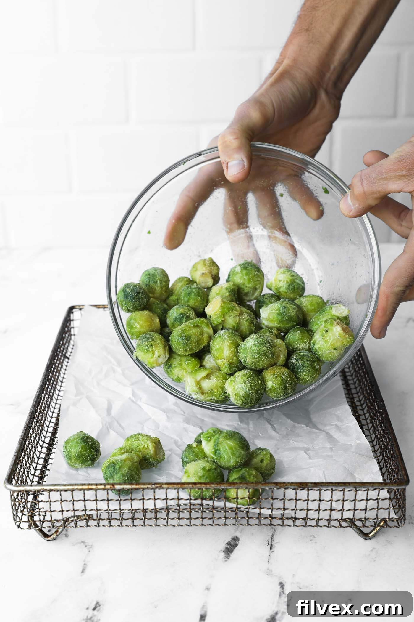 Spreading seasoned Brussels sprouts in a single layer in the air fryer basket.