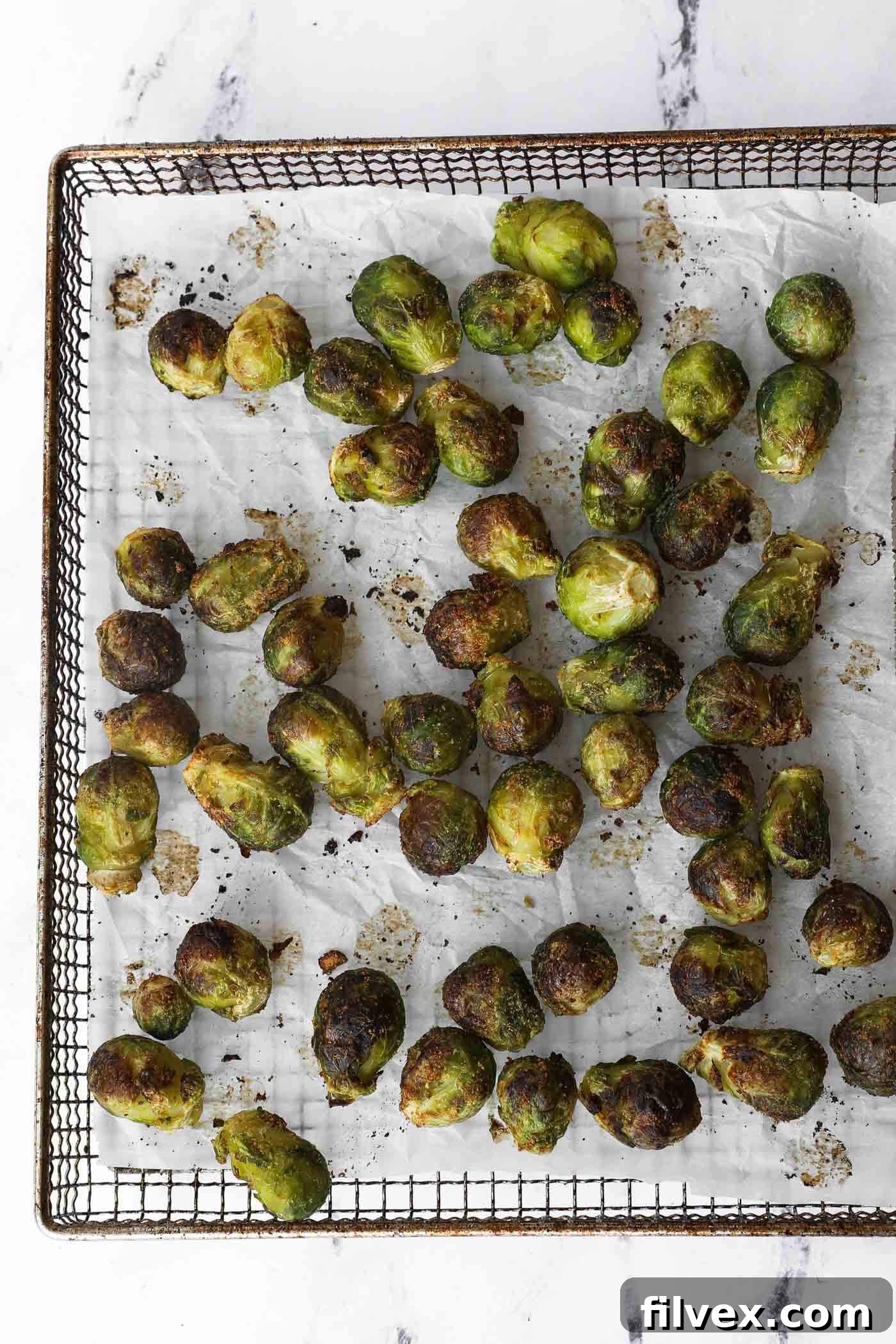Air frying Brussels sprouts, showing the cooking process and tossing mid-way.