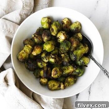 Bowl of cooked air fryer brussel sprouts from frozen with a balsamic vinegar drizzle.