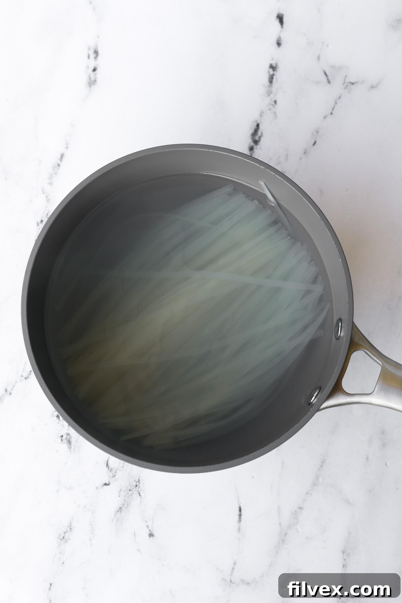 Fresh rice noodles are cooked until al dente, drained, and ready for the Pad Thai preparation.