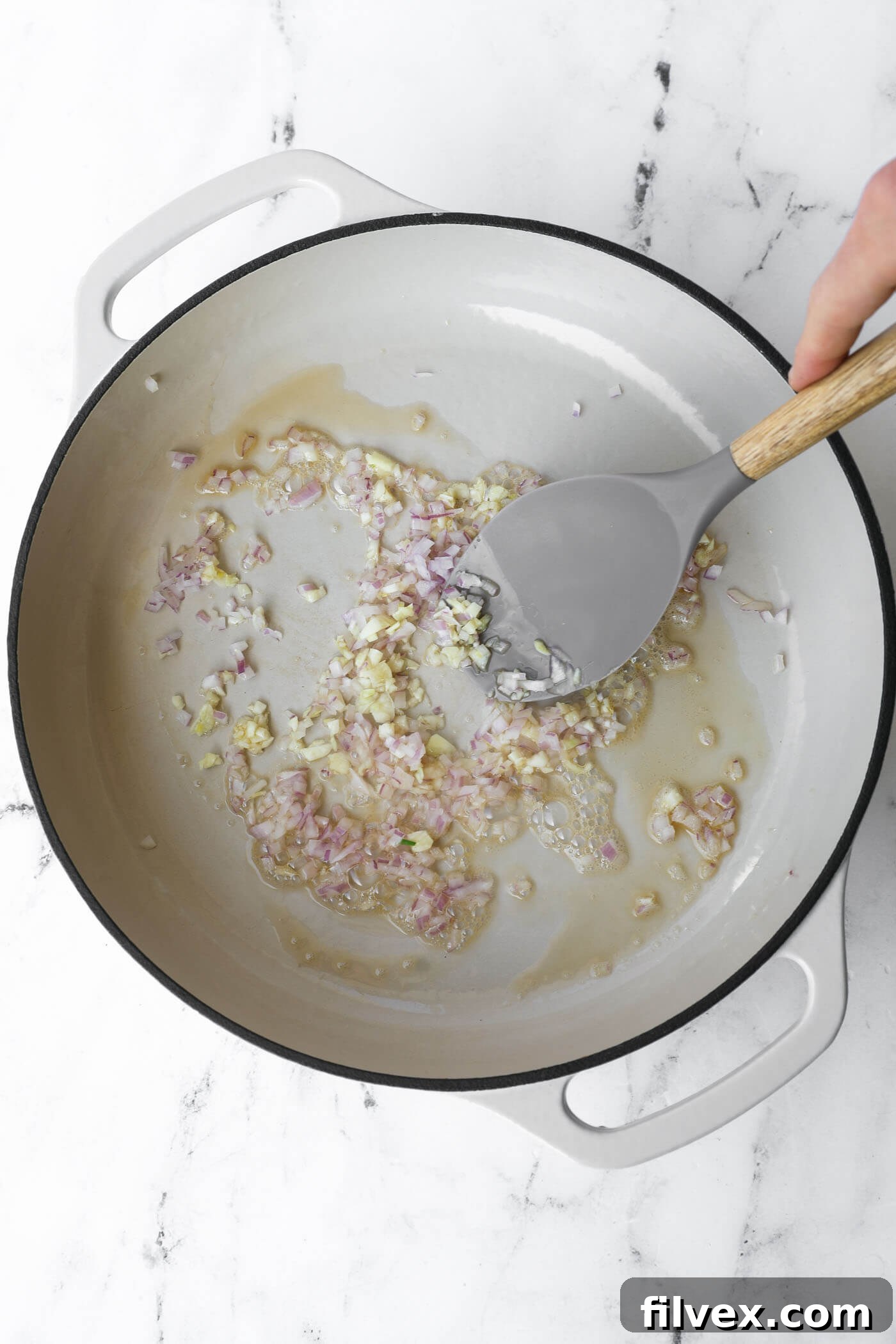 Shallots and garlic are gently sautéing in a hot skillet, releasing their fragrant aromas.