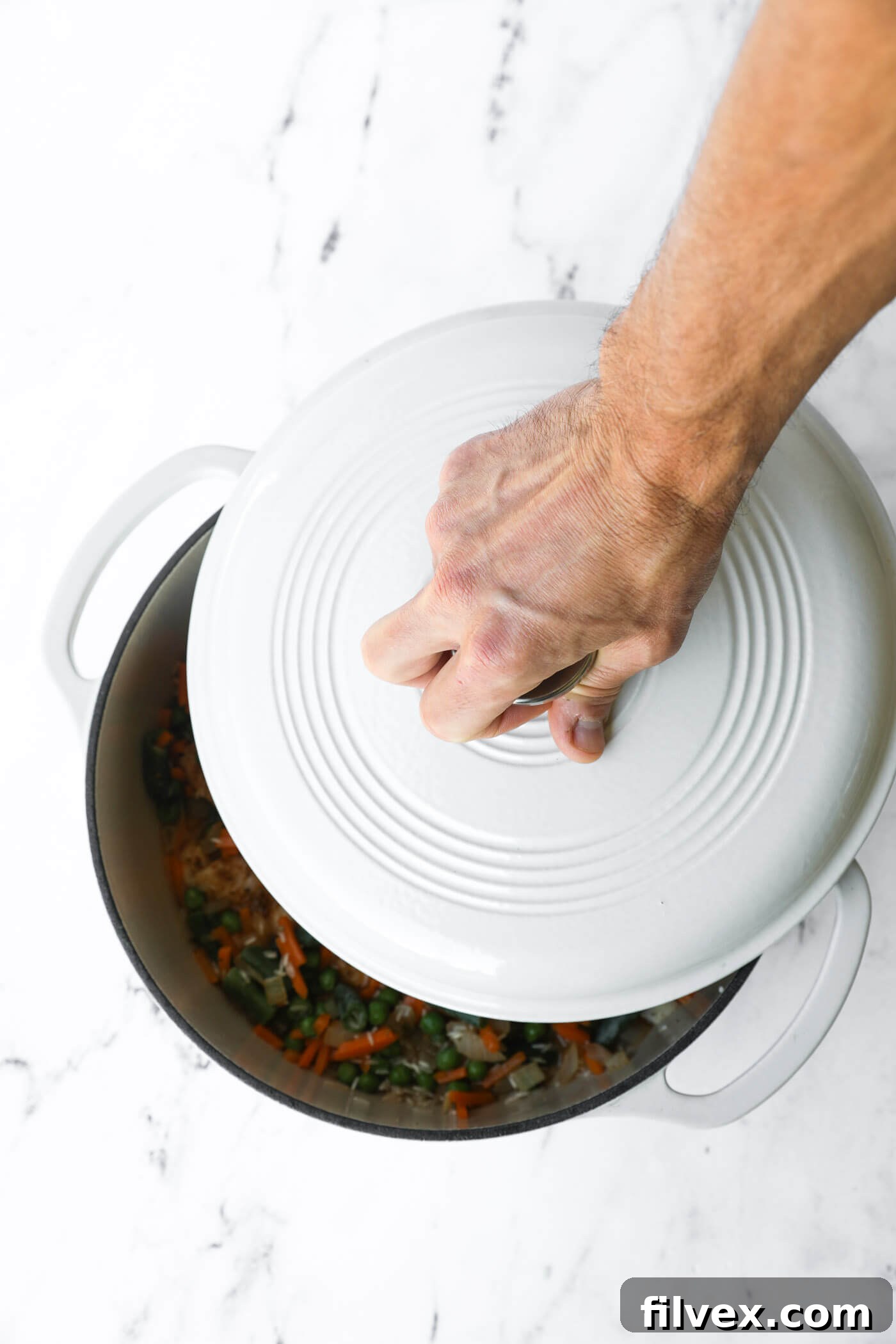 Hand placing lid on dutch oven.