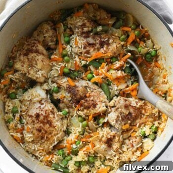 Overhead image of dutch oven chicken and rice with peas, onions and carrots.