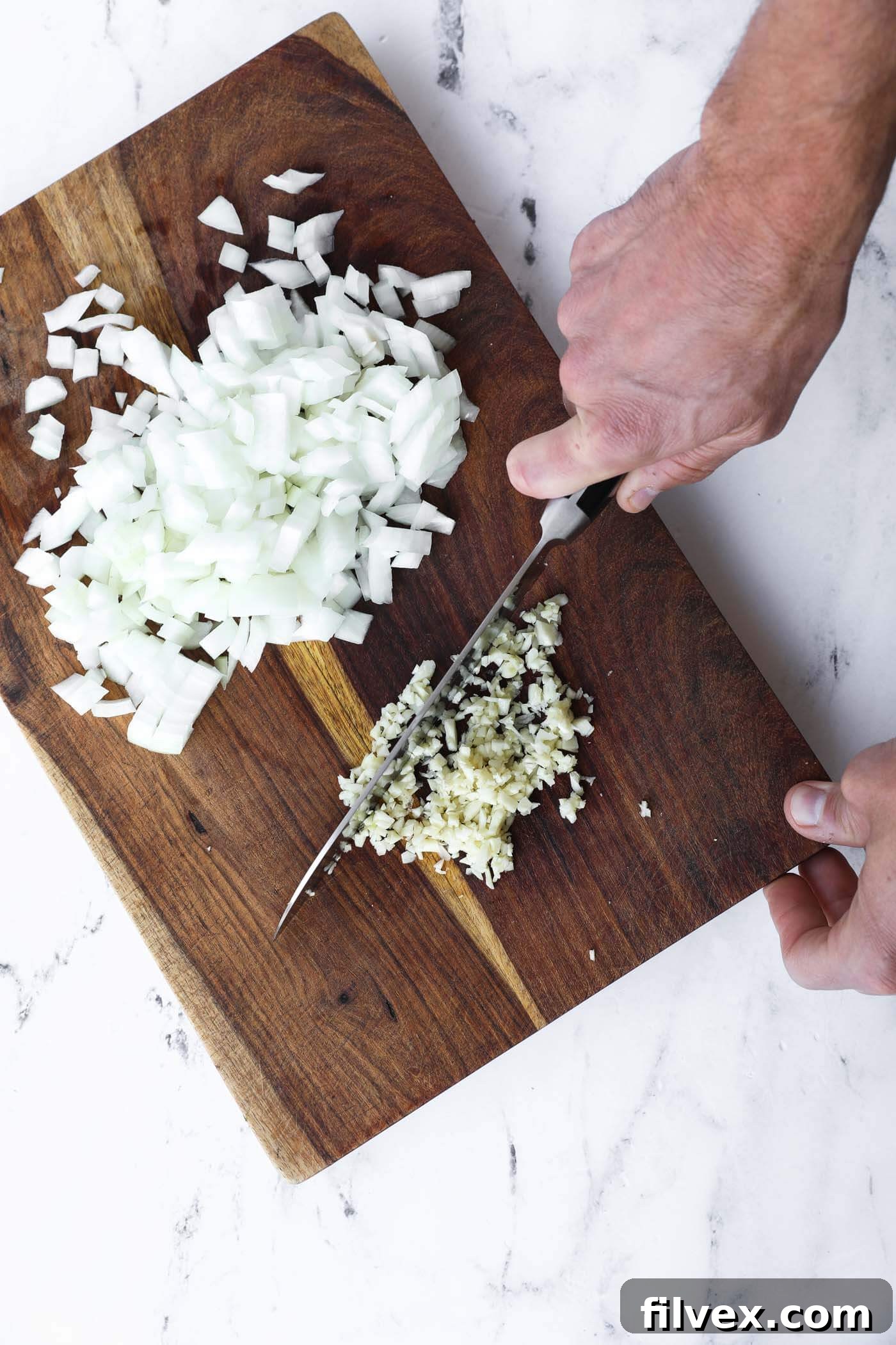 Garlic cloves and an onion are prepped, ready to be added to the dish.