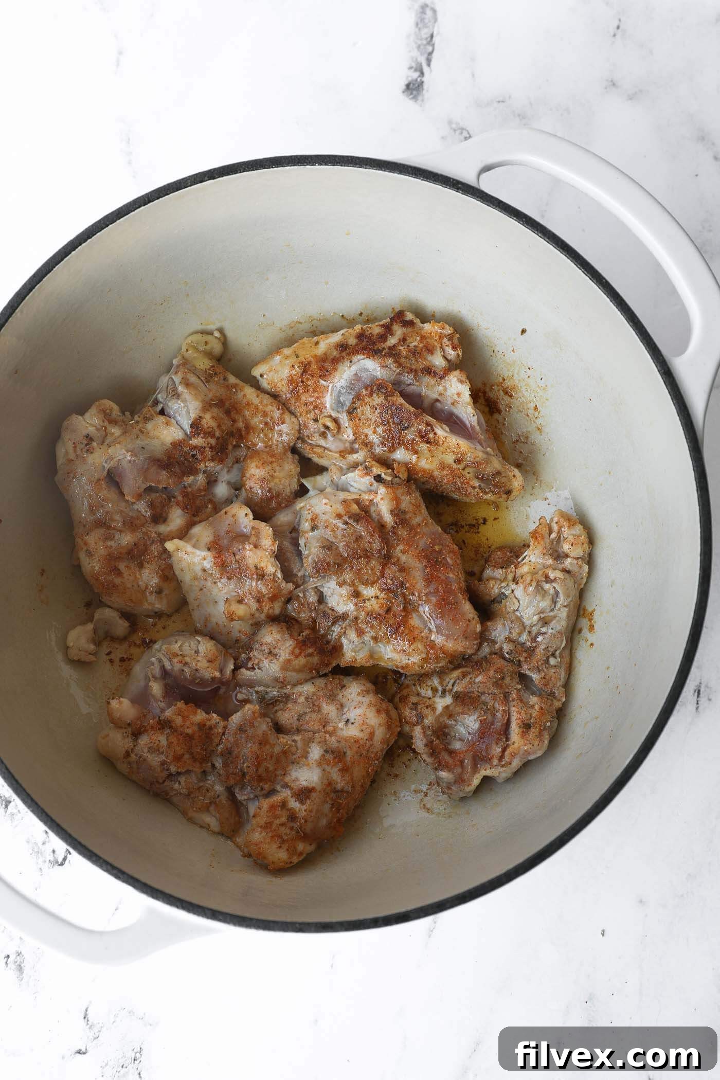 Chicken thighs are searing in a hot Dutch oven, developing a golden crust.