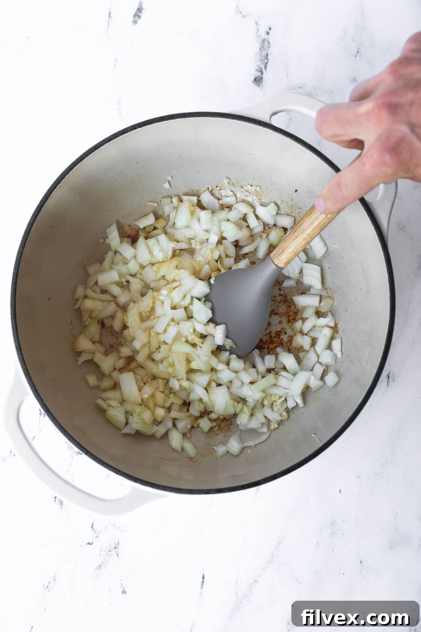 Diced onions and minced garlic are sautéing in the Dutch oven, releasing their aromas.
