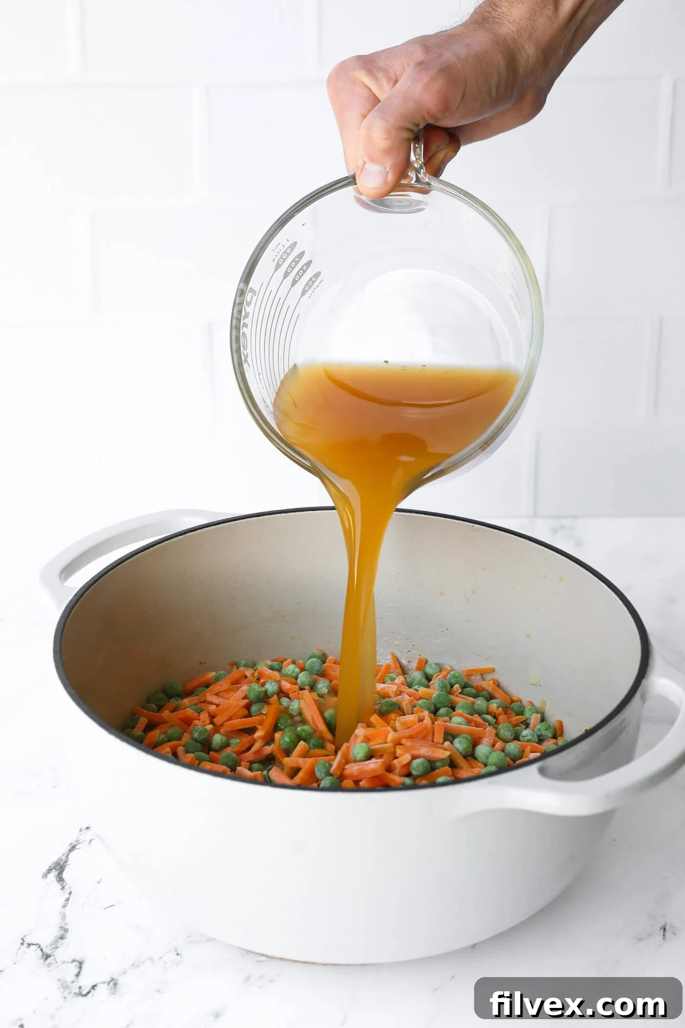 Rice, frozen vegetables, remaining seasoning, and broth are added to the Dutch oven.