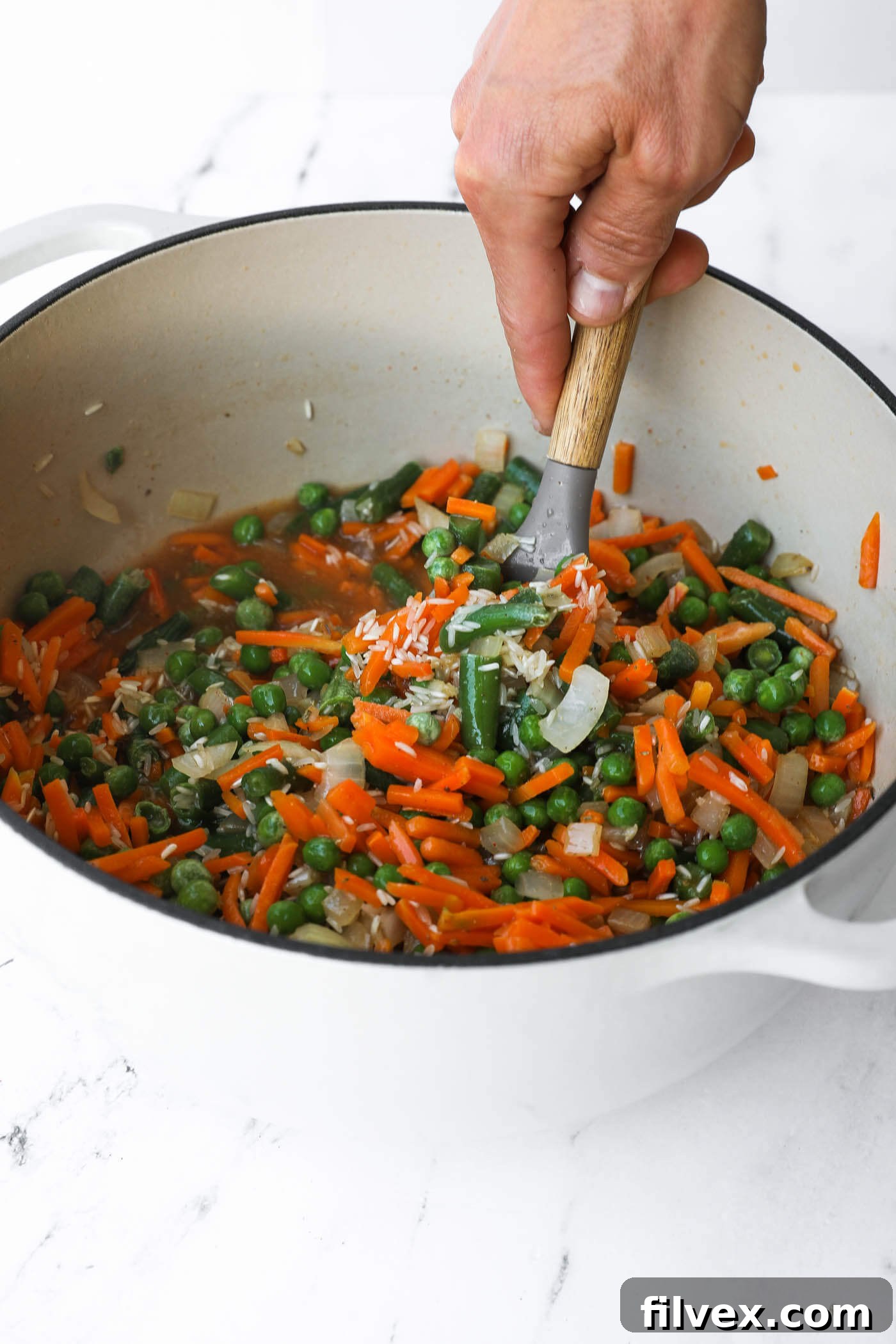 Ingredients are stirred in the Dutch oven to ensure rice is submerged in the liquid.